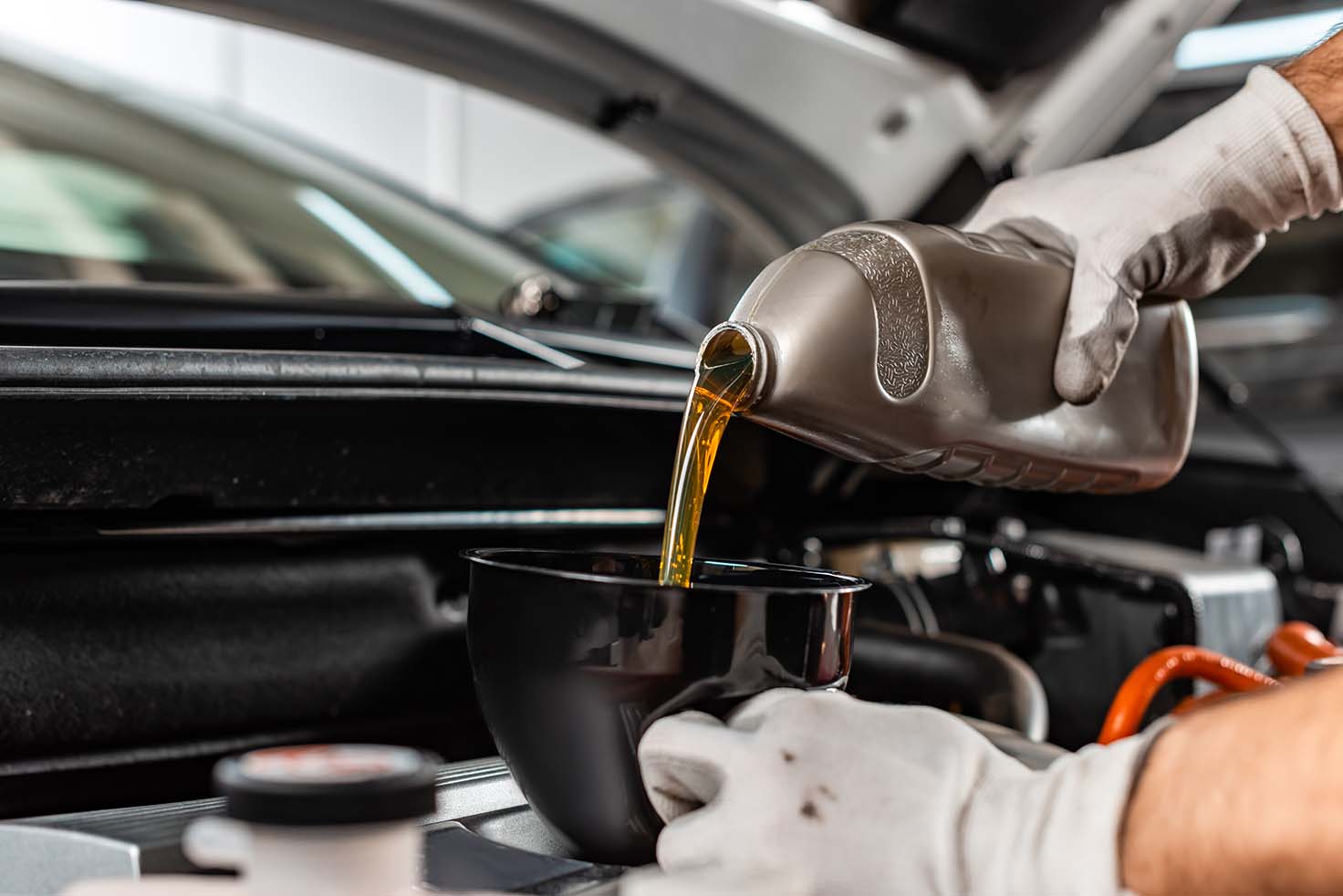 mechanic pouring motor oil at car engine