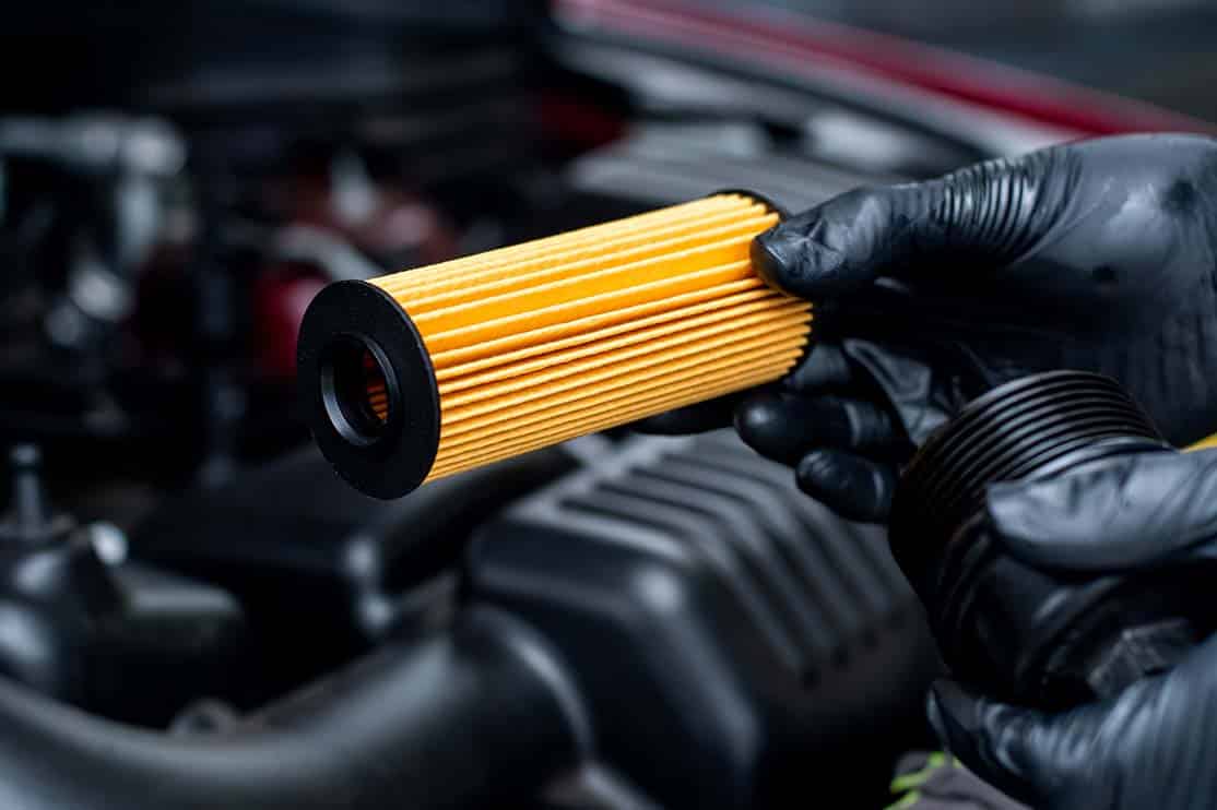 Mechanic installing new parts for the oil and filter change in a car engine.