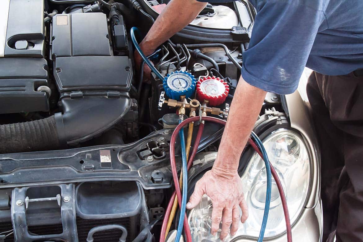 Mechanic inspecting and servicing a car's heating and air conditioning system.