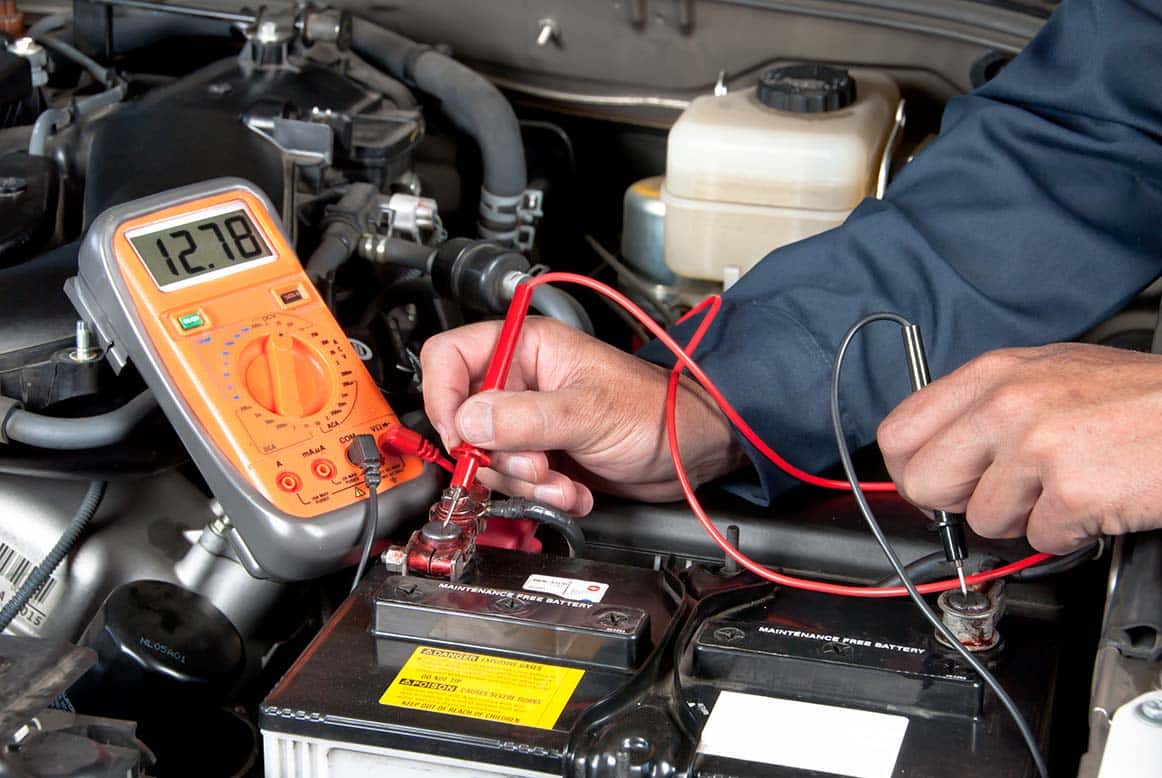Mechanic using diagnostic tool to test the battery's starting and charging system for optimal performance.