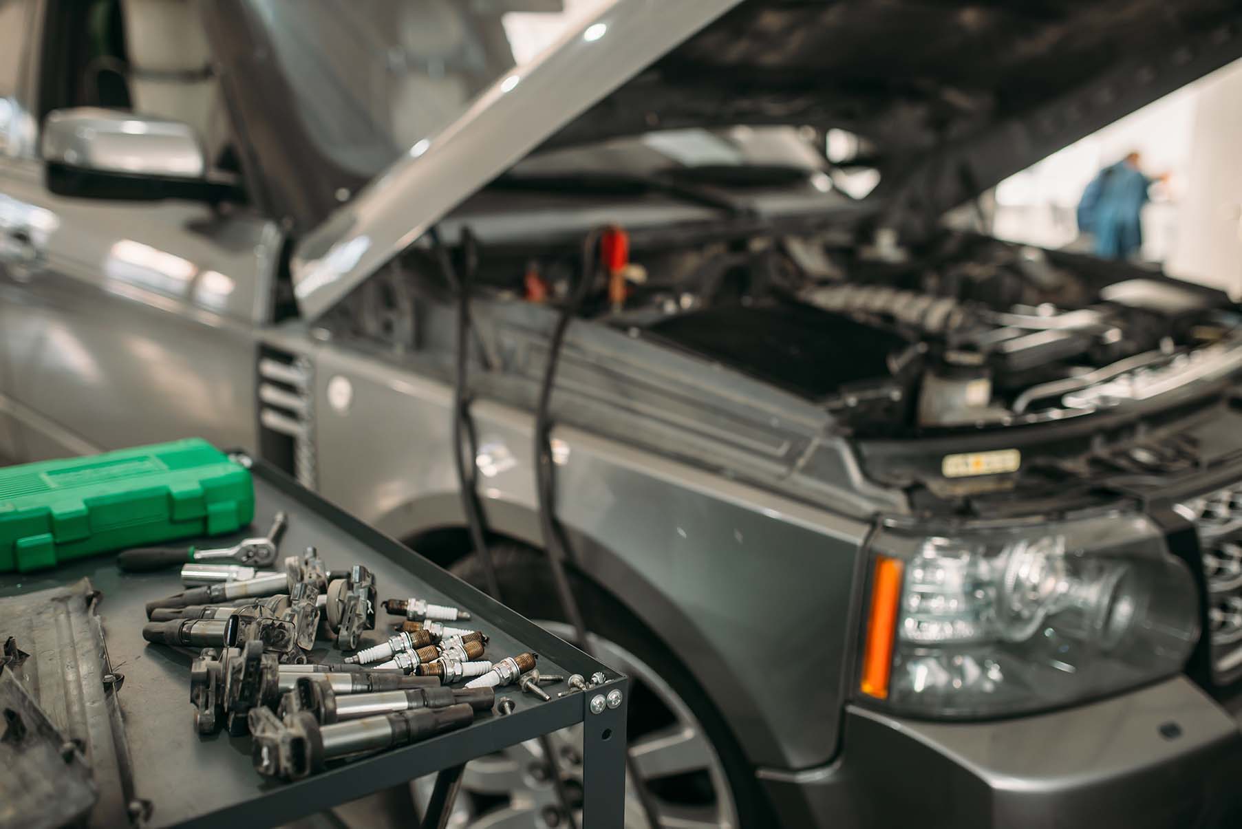 Car maintenance setup with an open-front vehicle, featuring tools and equipment neatly arranged on a table.