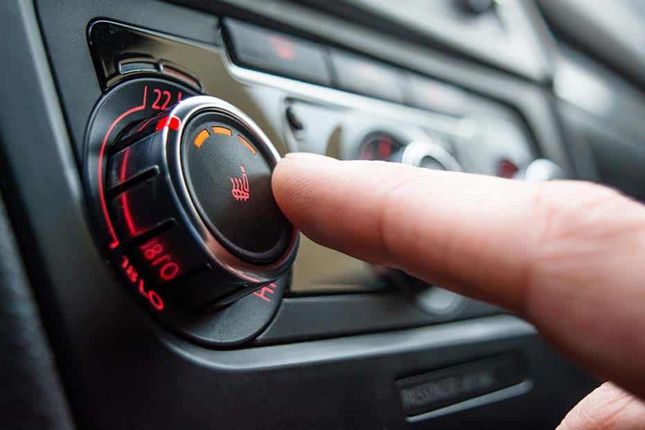 Driver adjusting the car's heating and air conditioning controls for personalized comfort.